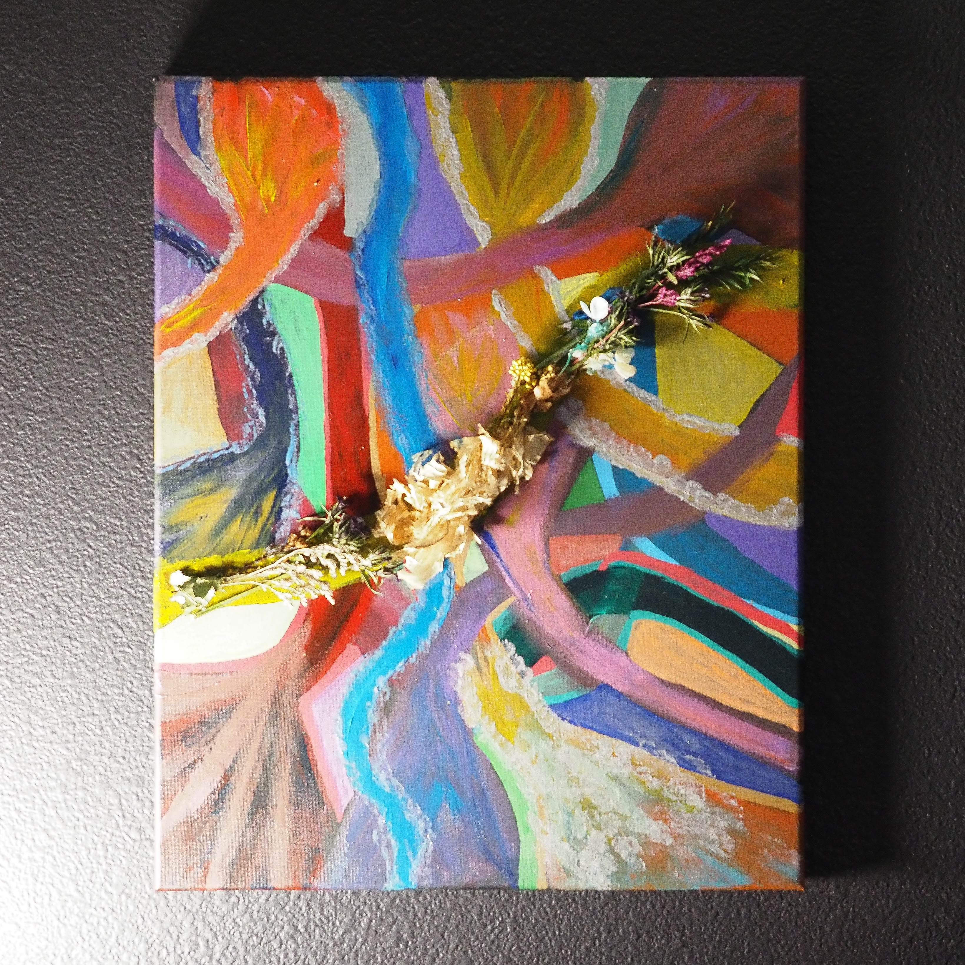 Abstract painting of overlapping colorful shapes with dried florals and bold lines.